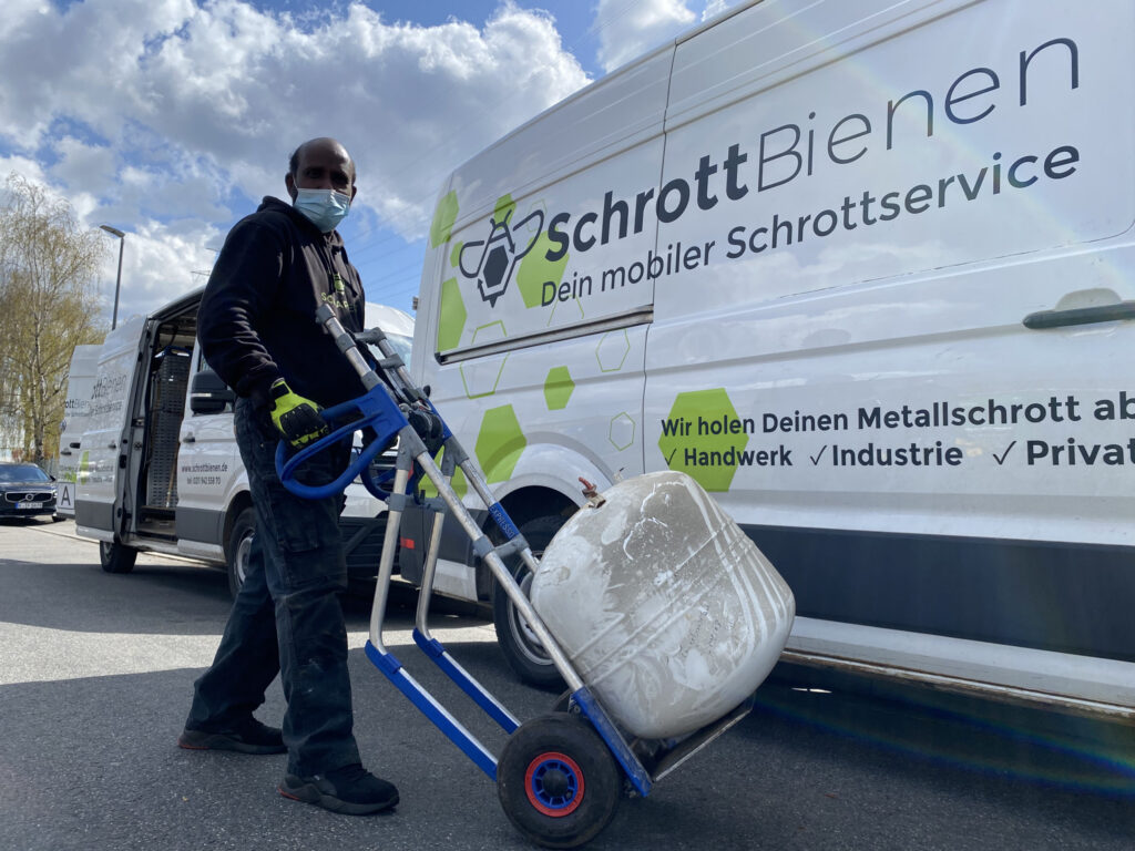 Das Bild zeigt einen Mitarbeiter der SchrottBienen beim Abtransport mit der Sackkarre.