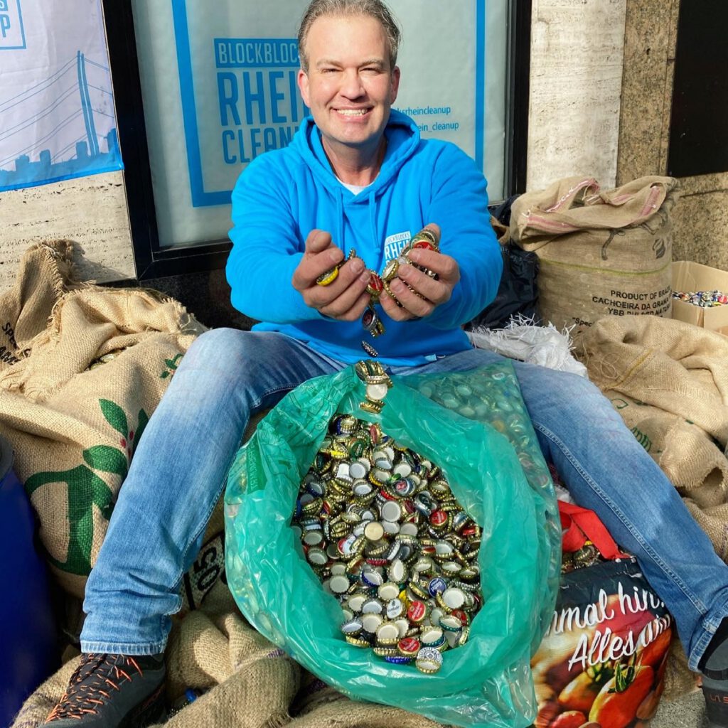 Das Bild zeigt einen Helfer von Blockblocks Cleanup, der auf mehreren Säcken voller Kornkorken sitzt.