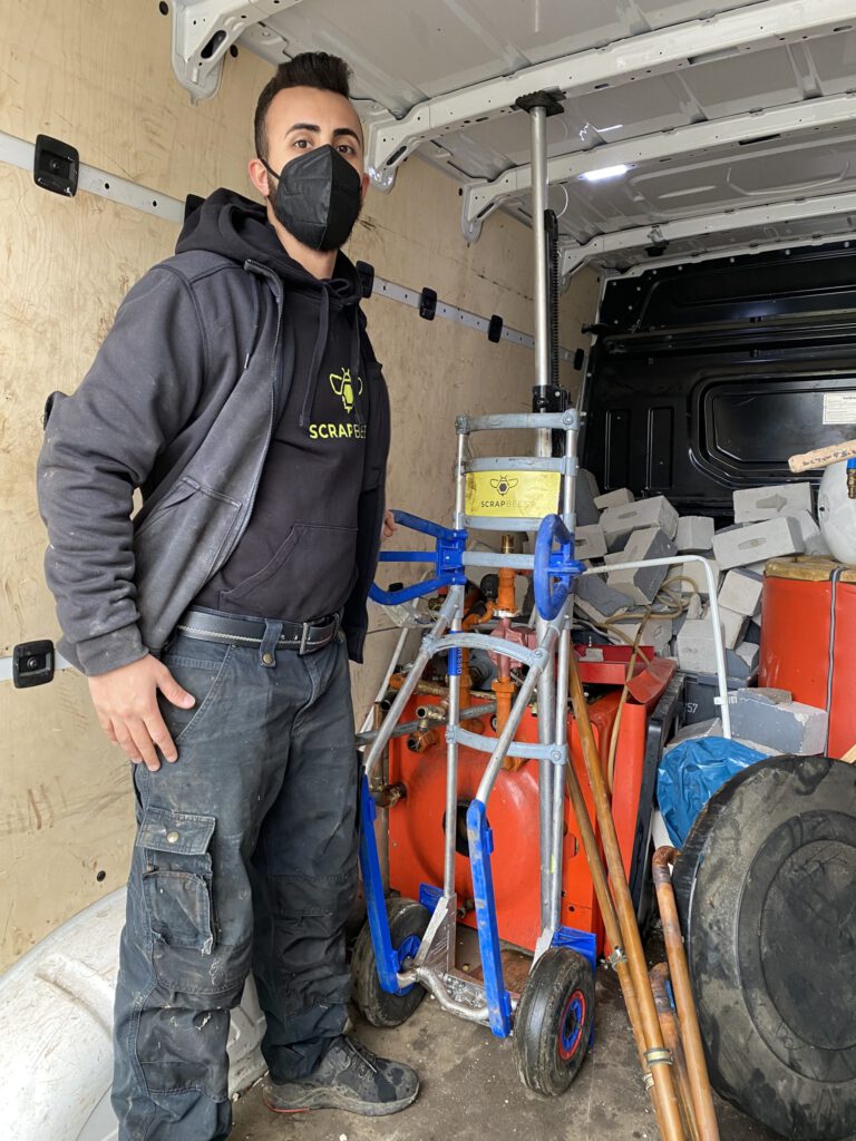 Das Bild zeigt einen Mitarbeiter der SchrottBienen bei der Arbeit mit der Sackkarre von Expresso.