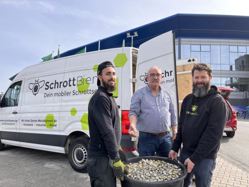 Das Bild zeigt einen Fahrer der SchrottBienen, Paul Steinebach und Gründer Thilo Hamm bei der Kronkorkenabholung auf Schalke.