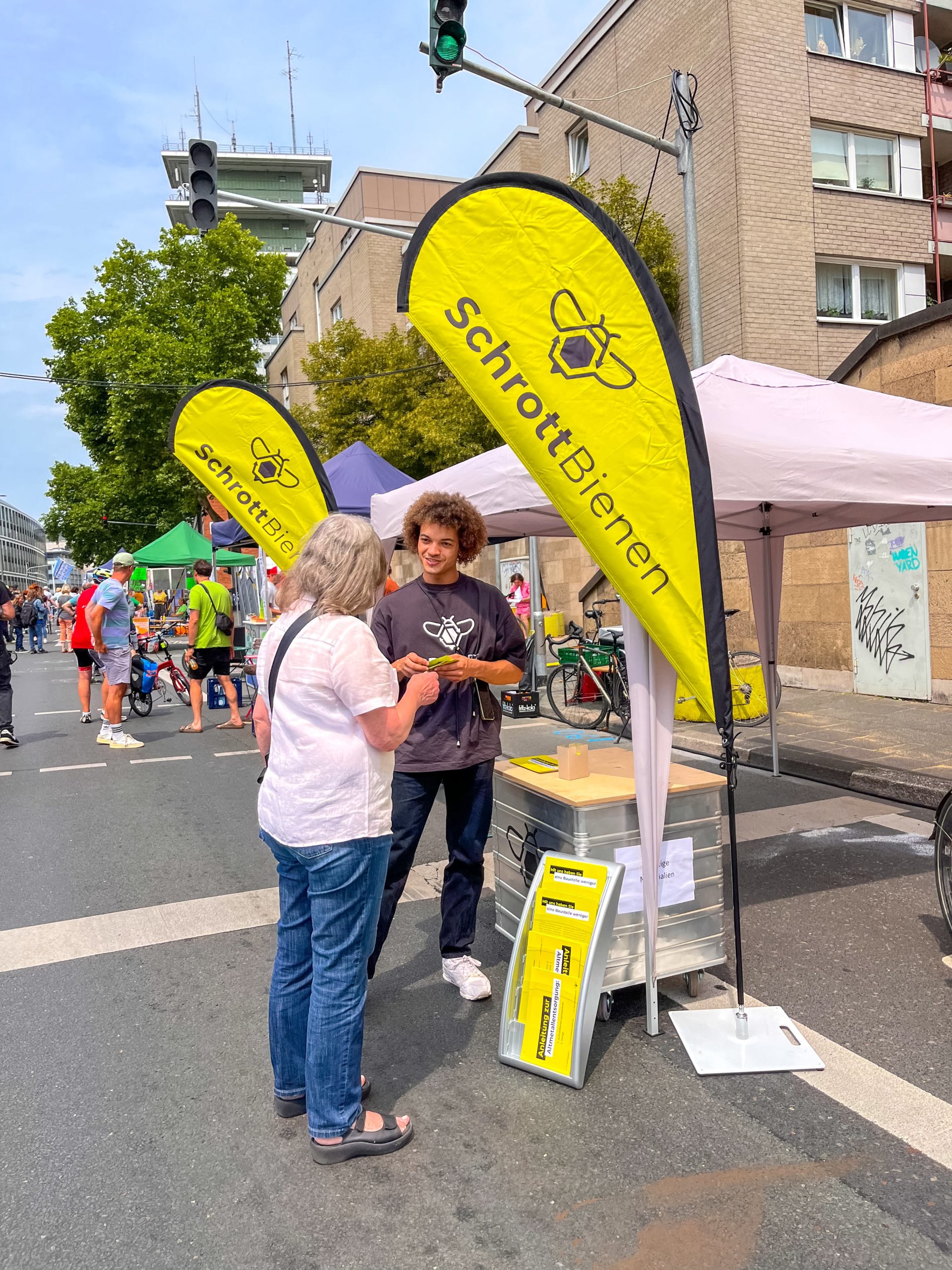 Das Bild zeigt einen Kollegen der ScrapBees im Gespräch mit einer Besucherin des Straßenfests.