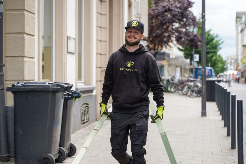 Das Bild zeigt einen Mitarbeiter der SchrottBienen, wie er Metallschrott bei einem Kunden abholt.