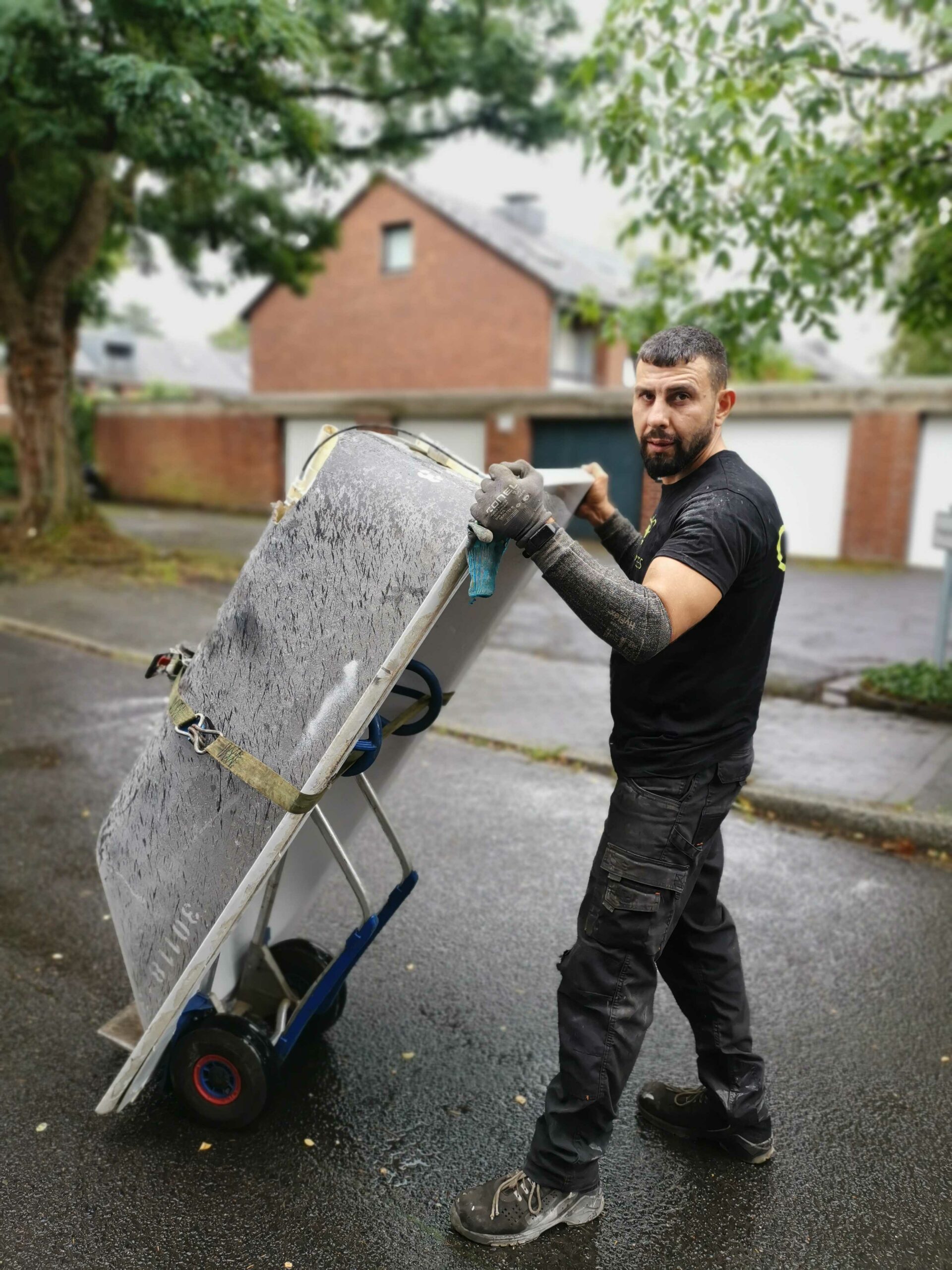 Das Bild zeigt einen Mitarbeiter des Schrotthändlers in Dortmund, der mit Hilfe einer Sackkarre eine alte Badewanne abtranportiert.