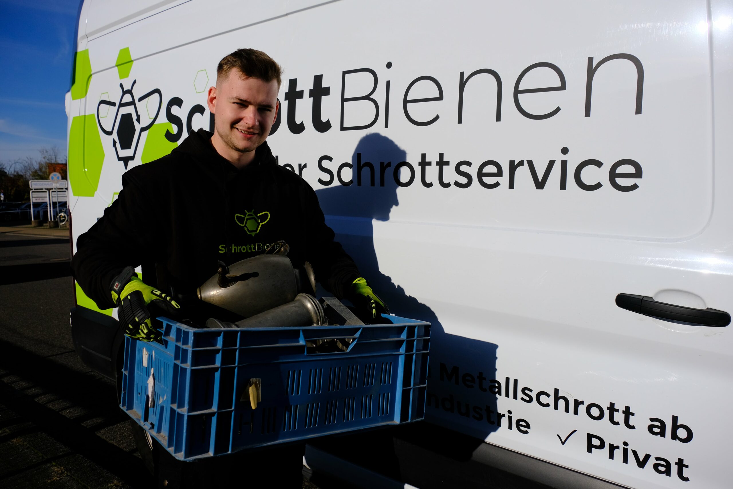 Das Bild zeigt einen Fahrer der SchrottBienen mit einer Kiste voll mit Zinngeschrirr in den Händen.