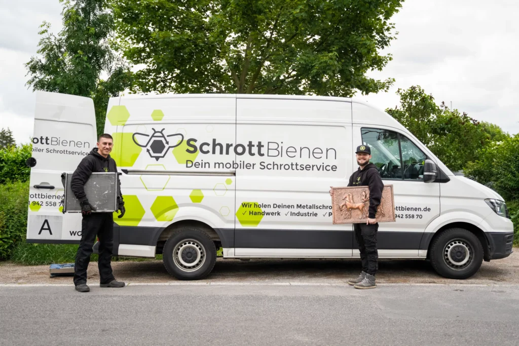 Das Bild zeigt zwei Fahrer der SchrottBienen mit etwas Altmetall in den Händen. Die Fahrer stehen vor einem Fahrzeug der SchrottBienen.
