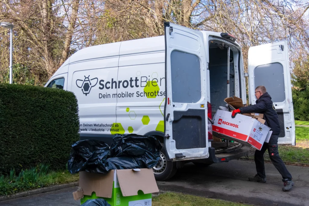 Das Bild zeigt einen Fahrer der SchrottBienen beim Verladen von Papiermüll.