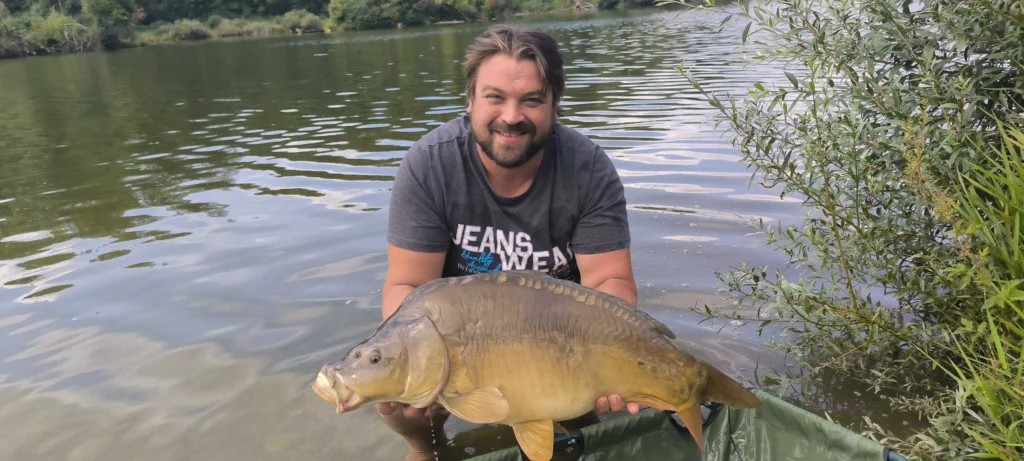 Das Bild zeigt Igor bei seiner Leidenschaft des Angelns. Er hält freudestrahlend einen großen Fisch in den Händen.