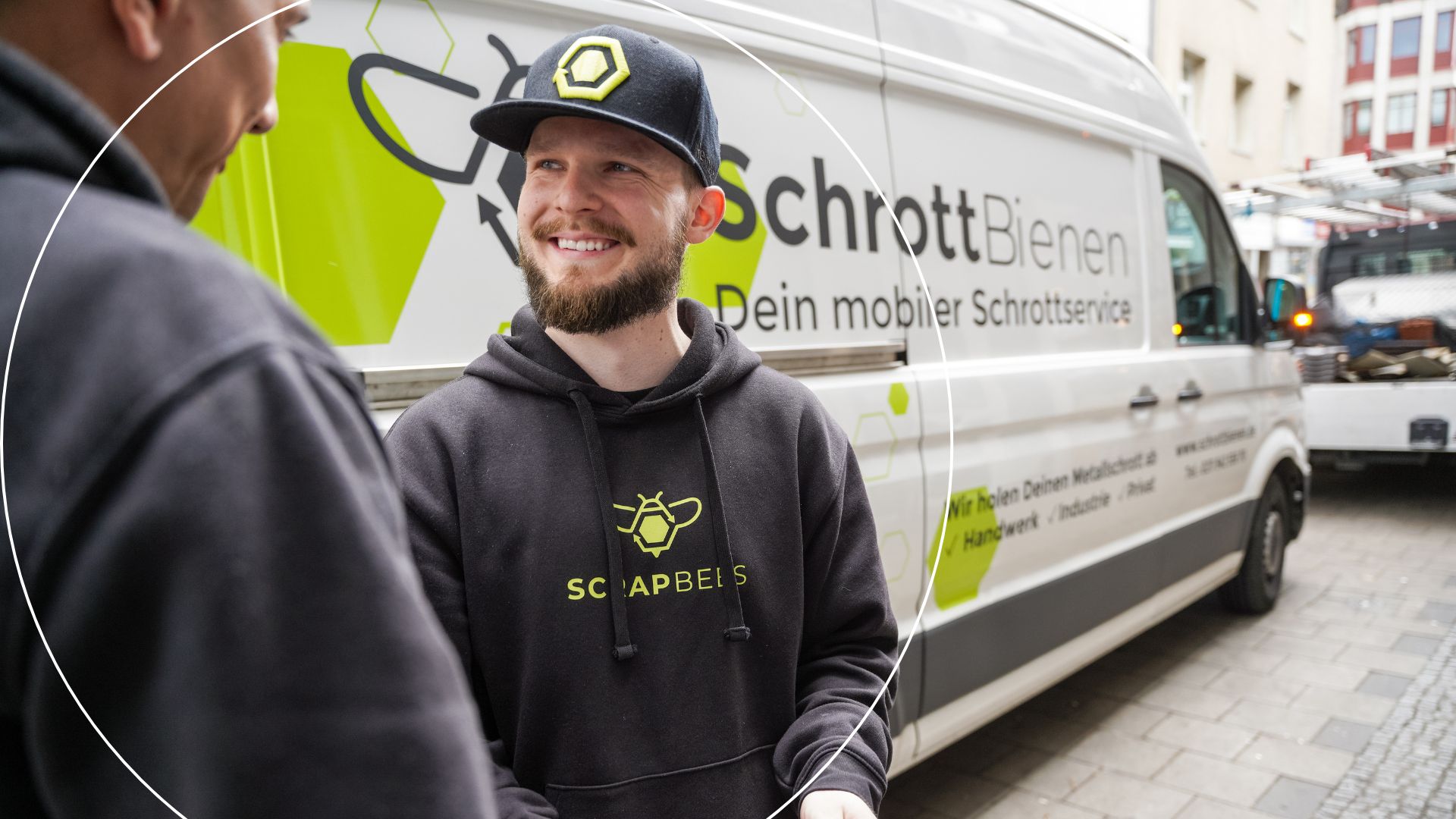 Das Bild zeigt einen Mitarbeiter der SchrottBienen im Gespräch mit einem Kunden. Die beiden stehen vor einem Fahrzeug des Unternehmens. In der Hand hält der Fahrer ein Tablet.